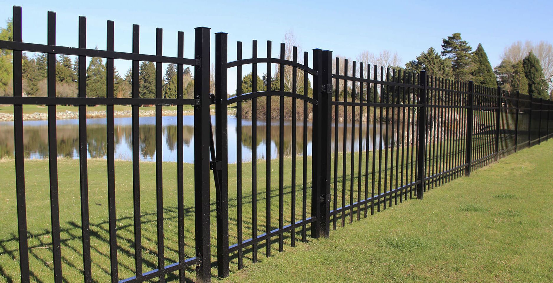 Ornamental aluminum fence with decorative arched gate near water feature